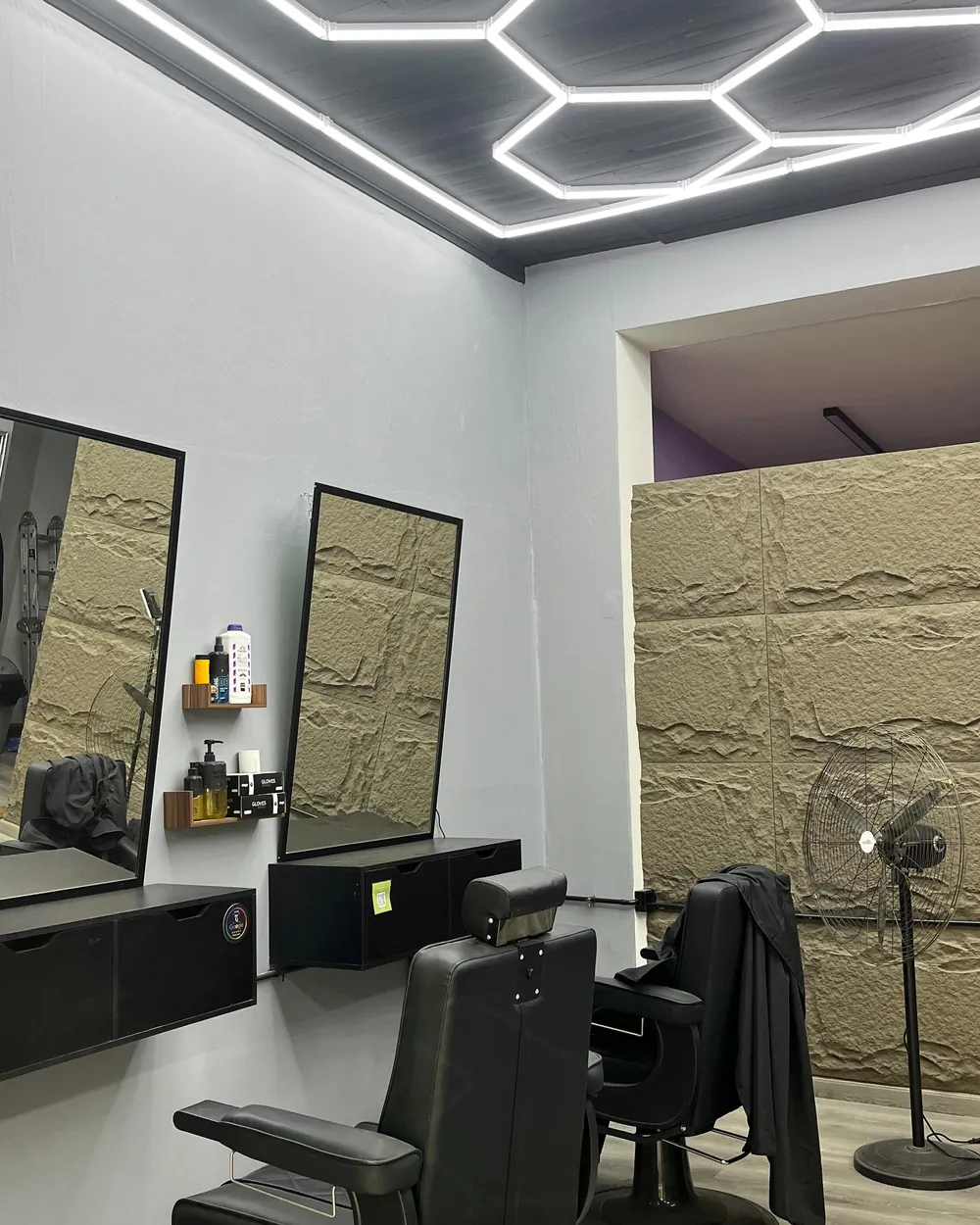 Interior de Barbería O'Higgins: sillas, espejos y luces hexagonales